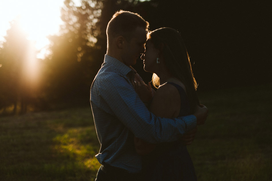 przytulająca się para podczas sesji narzeczeńskiej o wschodzie słońca w lesie